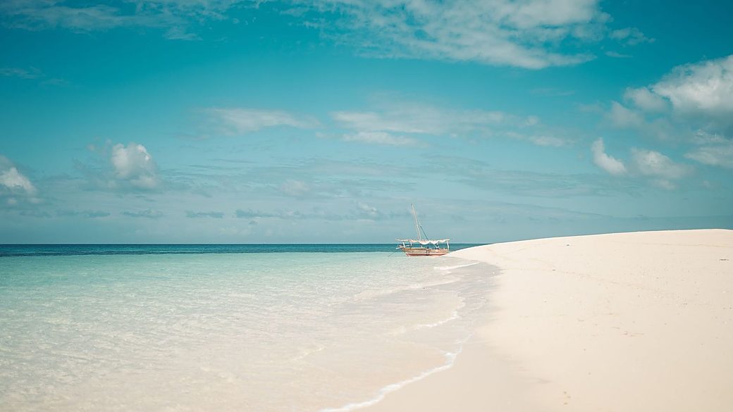 A traditional dhow moored at a white sandbank