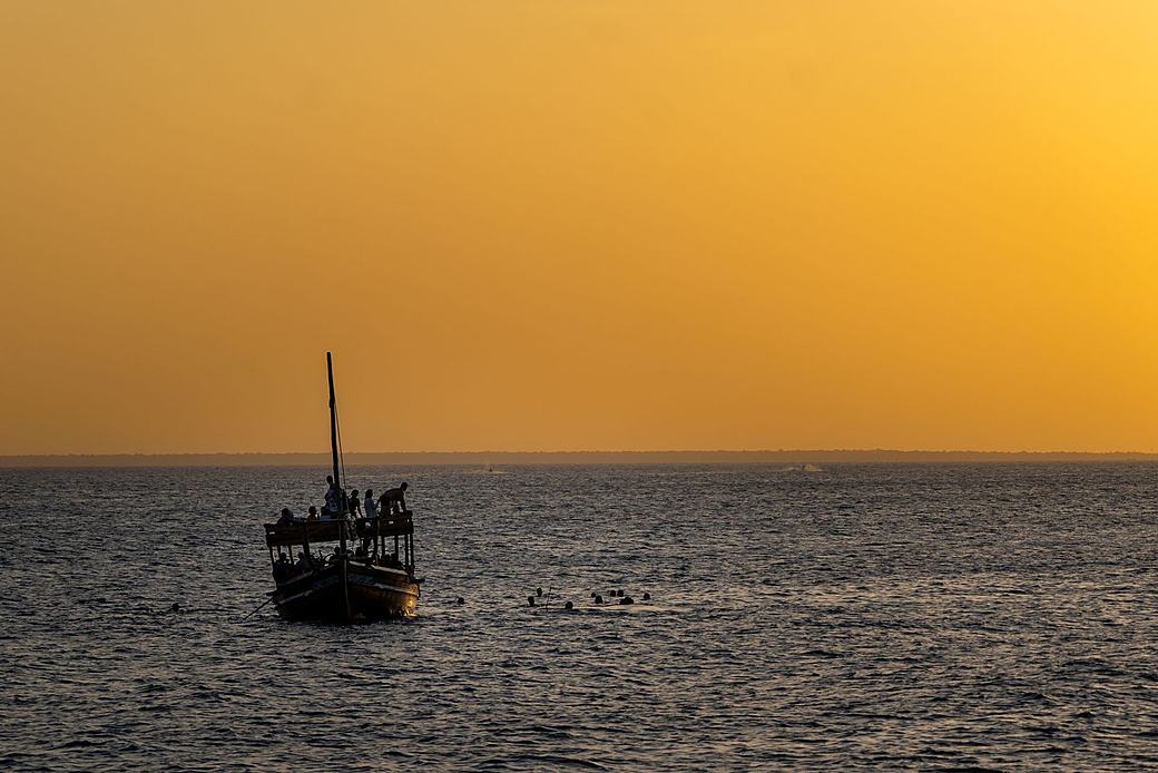 A dhow silhouetted against a golden Zanzibar sunset
